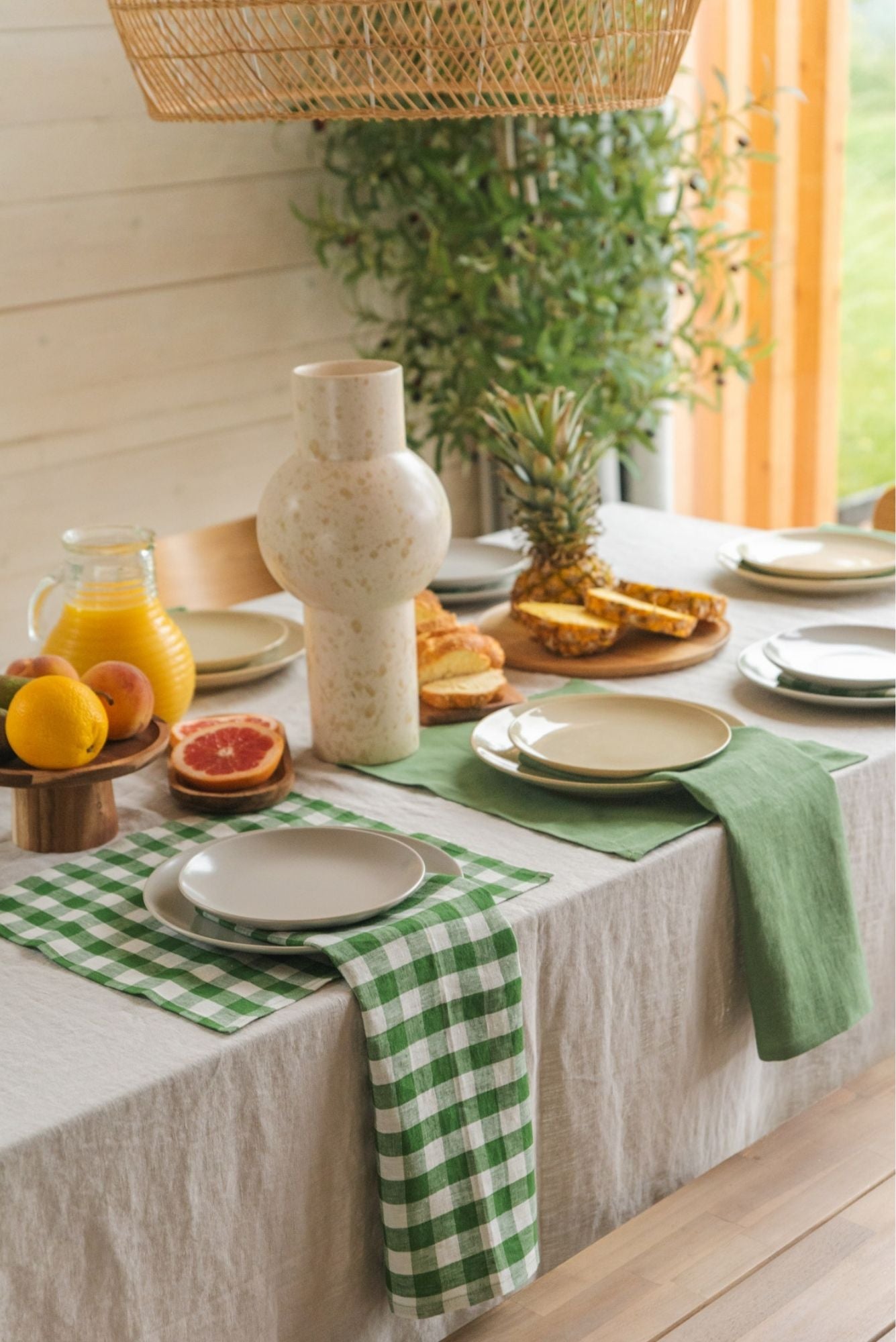 Two 100% linen napkins in a green gingham pattern and green color, neatly folded and displayed on a neutral tablecloth